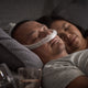 Man sleeping with ResMed AirFit P30 and his partner on the side.