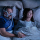 Couple sleeping and man wearing CPAP Airtouch mask.