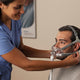 Nurse fitting the Respironics Amara mask to the man sitting in front of her