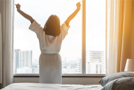Woman stretching while looking out her bedroom window