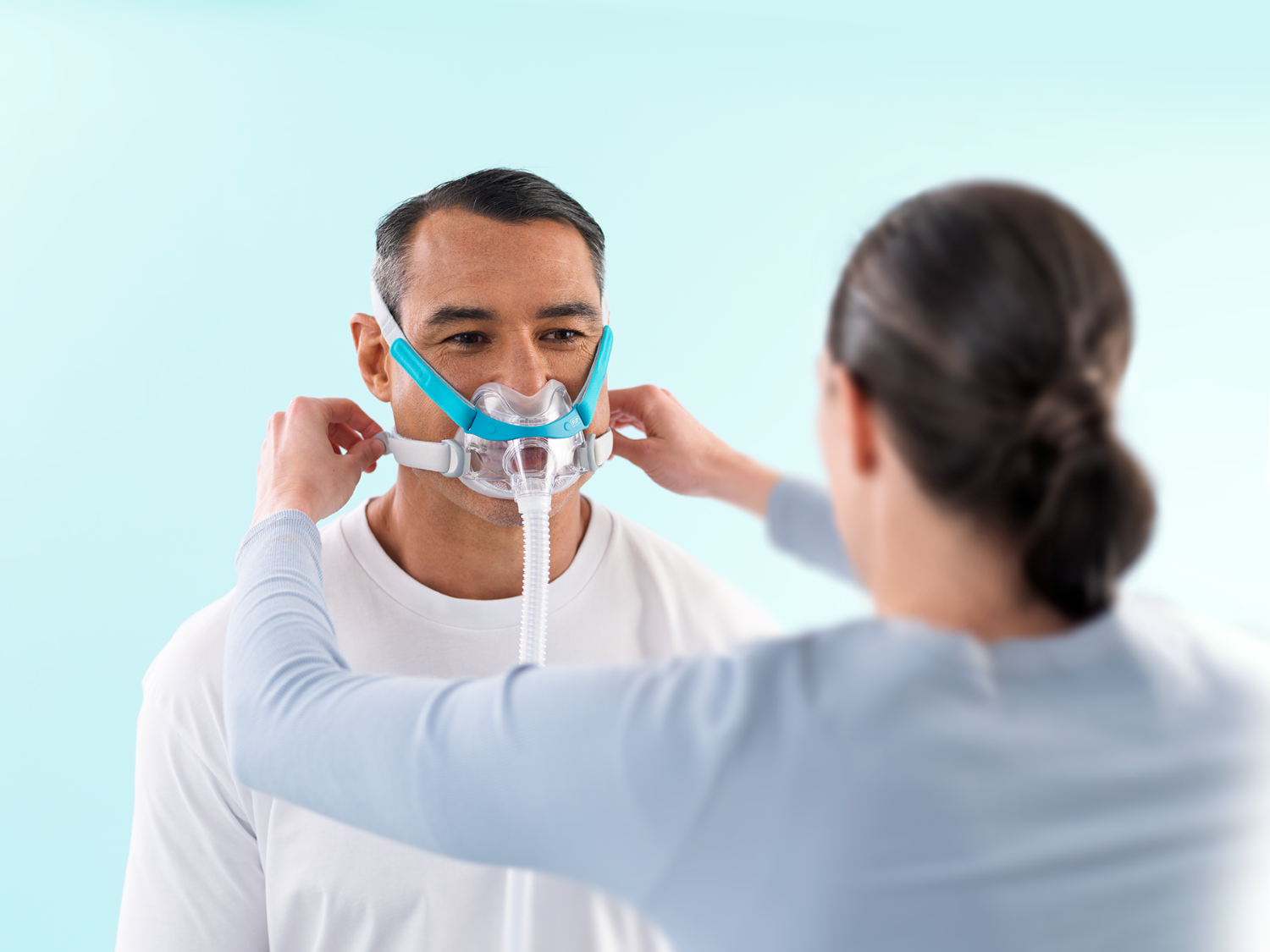 Woman adjusting a male's CPAP Mask