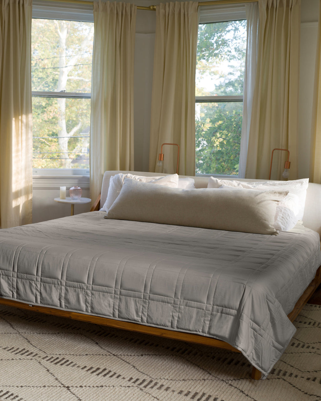Gray Baloo weighted comforter spread across a king bed in a sunlit bedroom