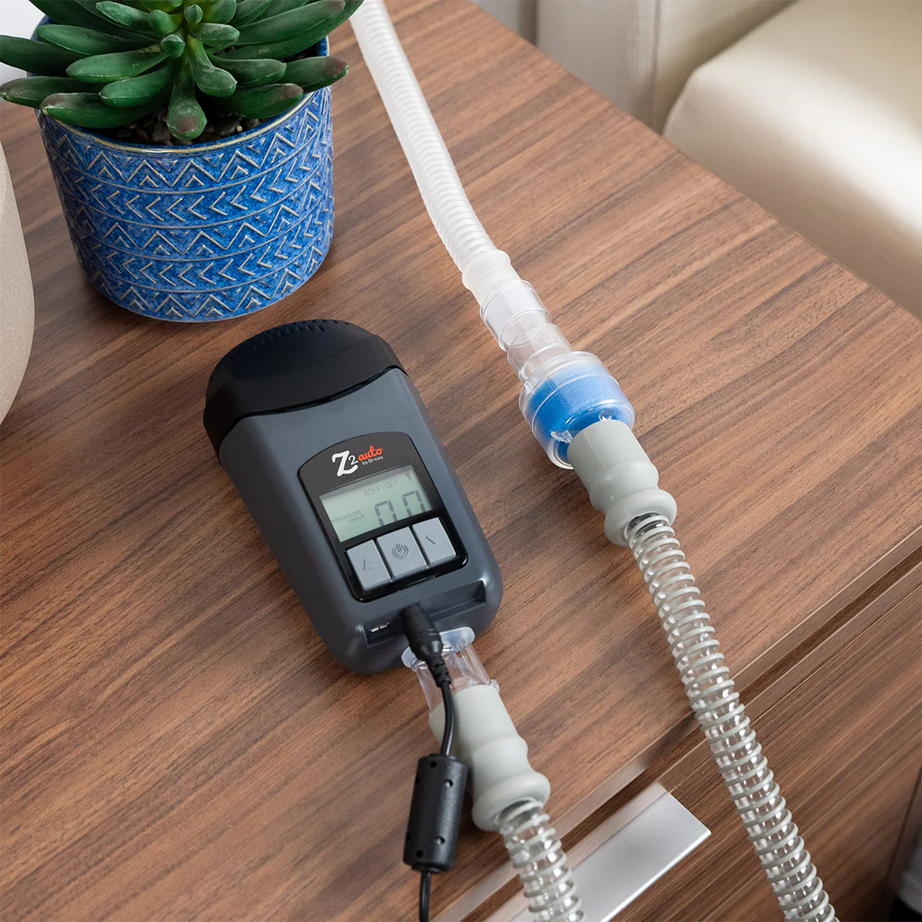 Breas HME canister connected inline on CPAP tubing with a Breas Z2 Auto on a nightstand, showing waterless humidification setup for travel