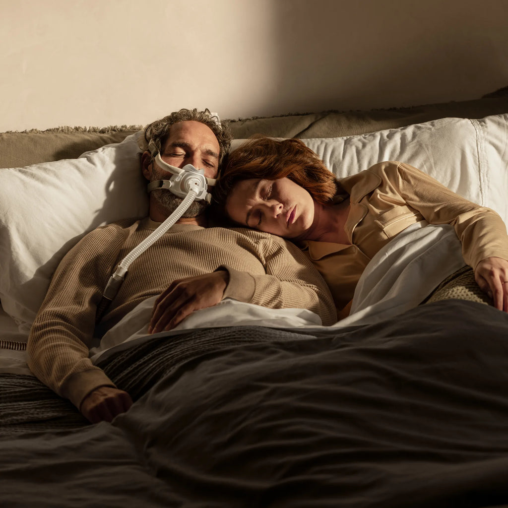 Couple sleeping in bed, one partner wearing the ResMed AirTouch F40 full face mask