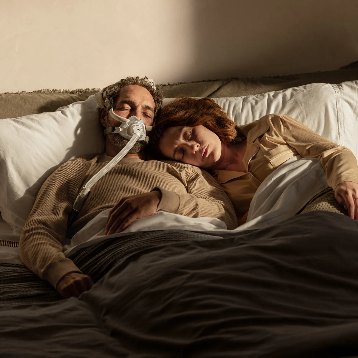 Couple sleeping in bed, one partner wearing the ResMed AirTouch F40 full face mask