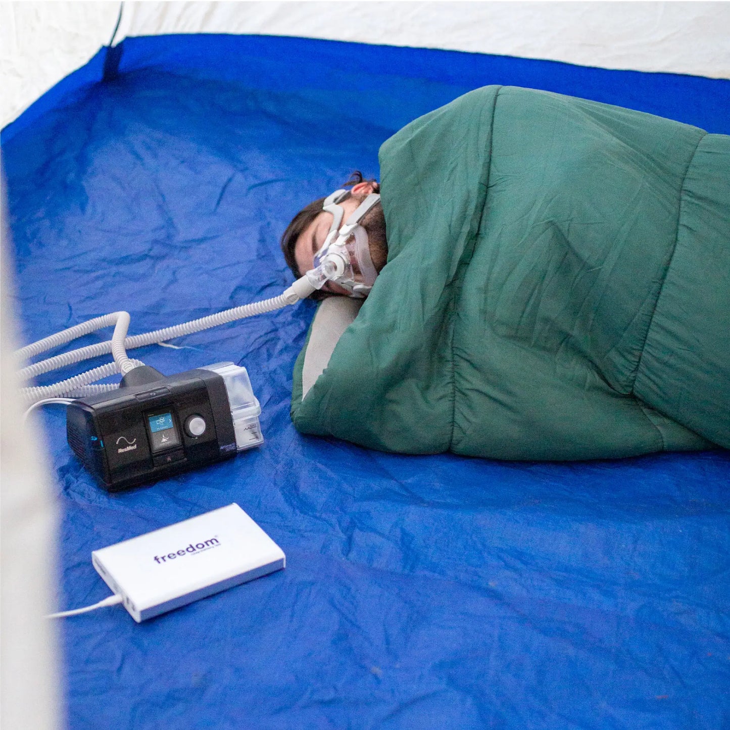 Man camping with his CPAP machine powered by the Freedom 160 Battery Backup, showcasing its portability."