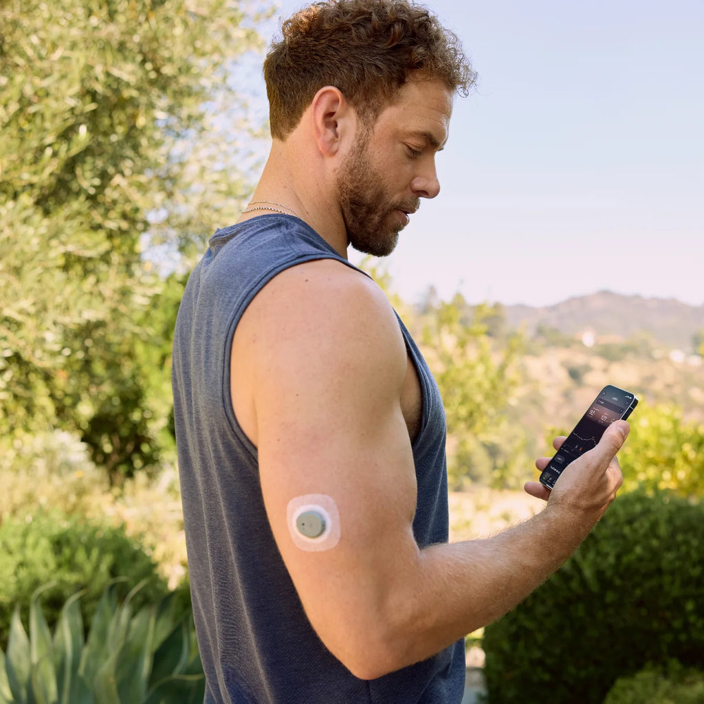 Man outdoors checks the Stelo app, Dexcom Stelo biosensor visible on the back of his upper arm