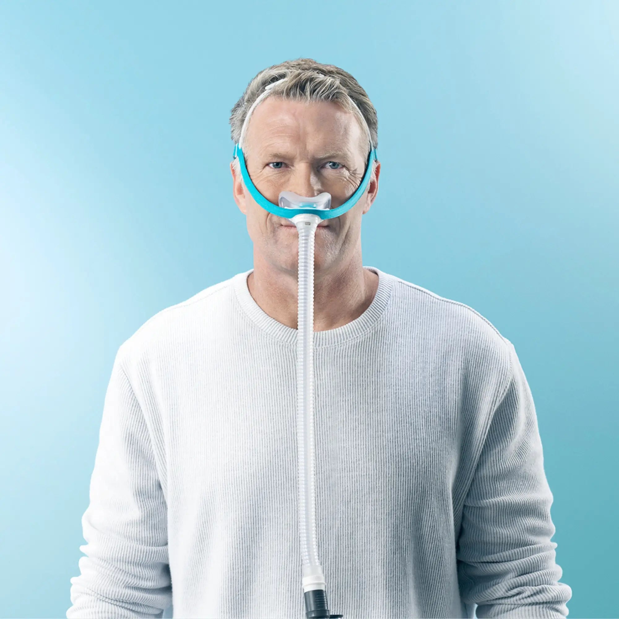 Man facing forward wearing the Fisher and Paykel Evora nasal CPAP mask against a light blue background