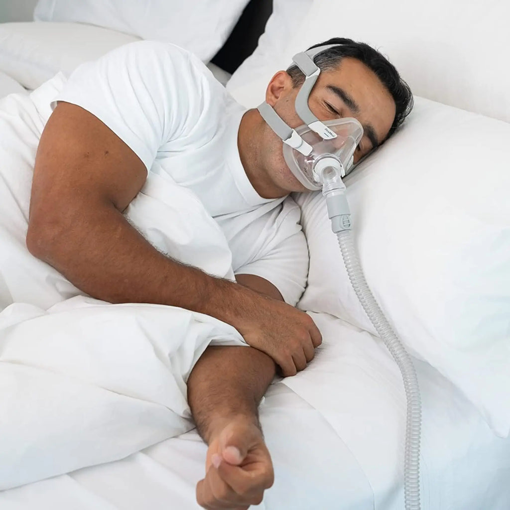 Man side sleeping in bed wearing a CPAP mask connected to Snugell 8 foot standard tubing