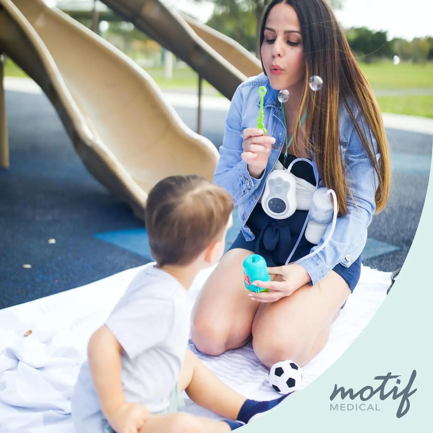 Mother using the Motif Duo Double Electric Breast Pump discreetly while sitting on a park, demonstrating its portability and ease of use outdoors.