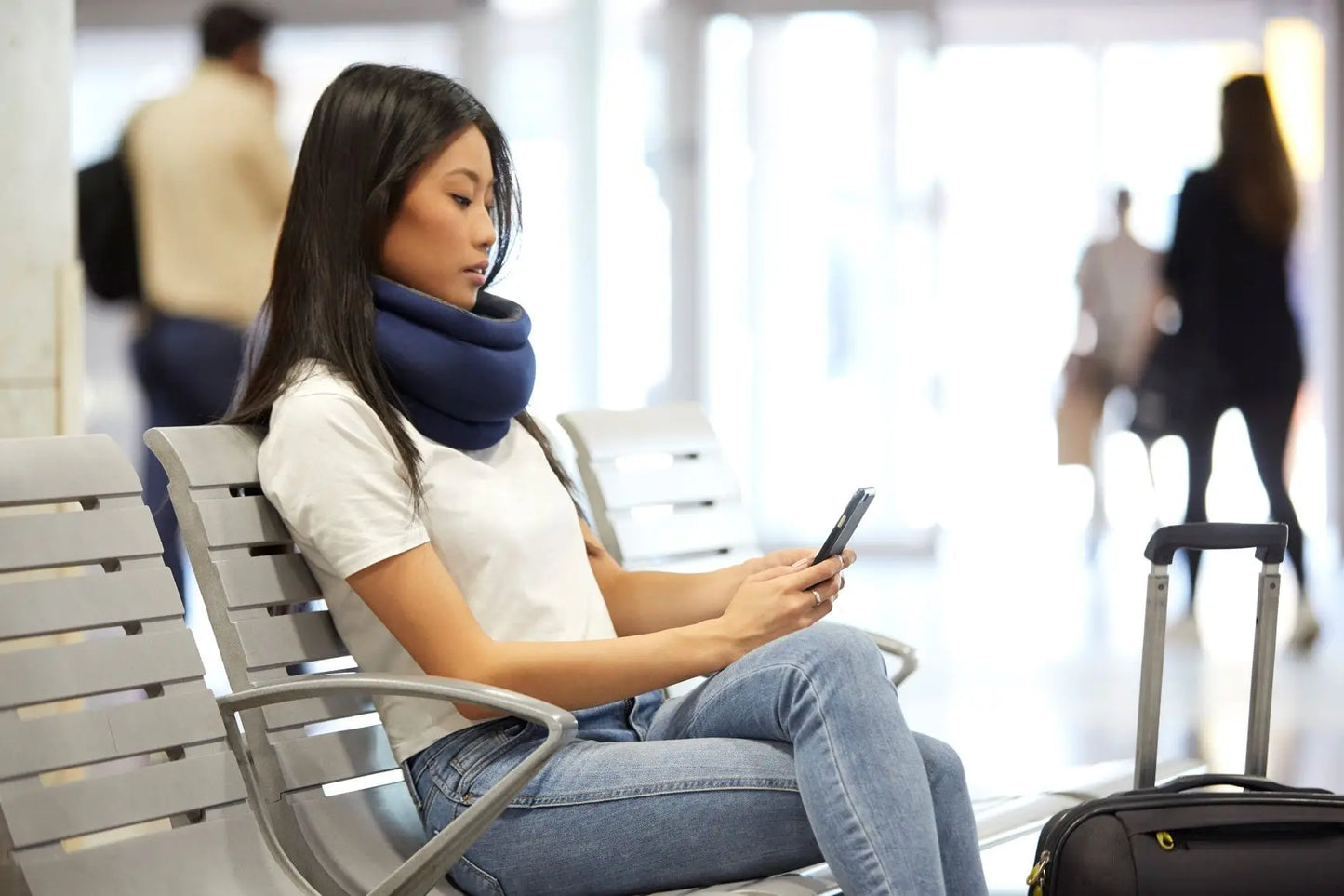 Woman using the Light Versatile Travel Pillow while using the cellphone in the airport