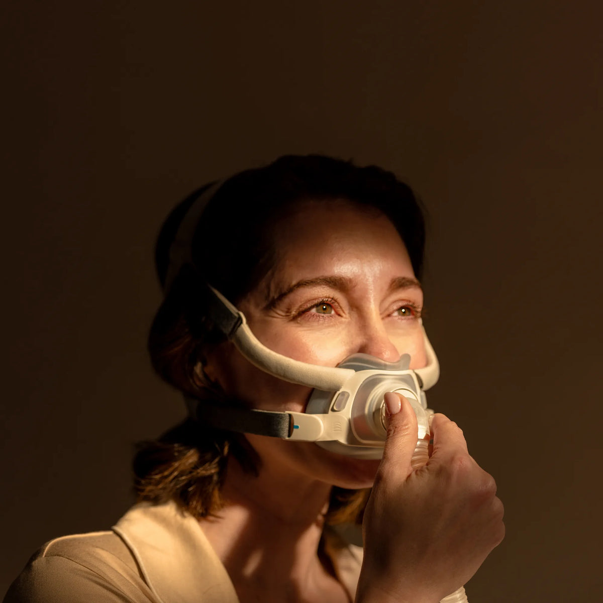 Woman putting on the ResMed AirTouch F40 full face mask at night
