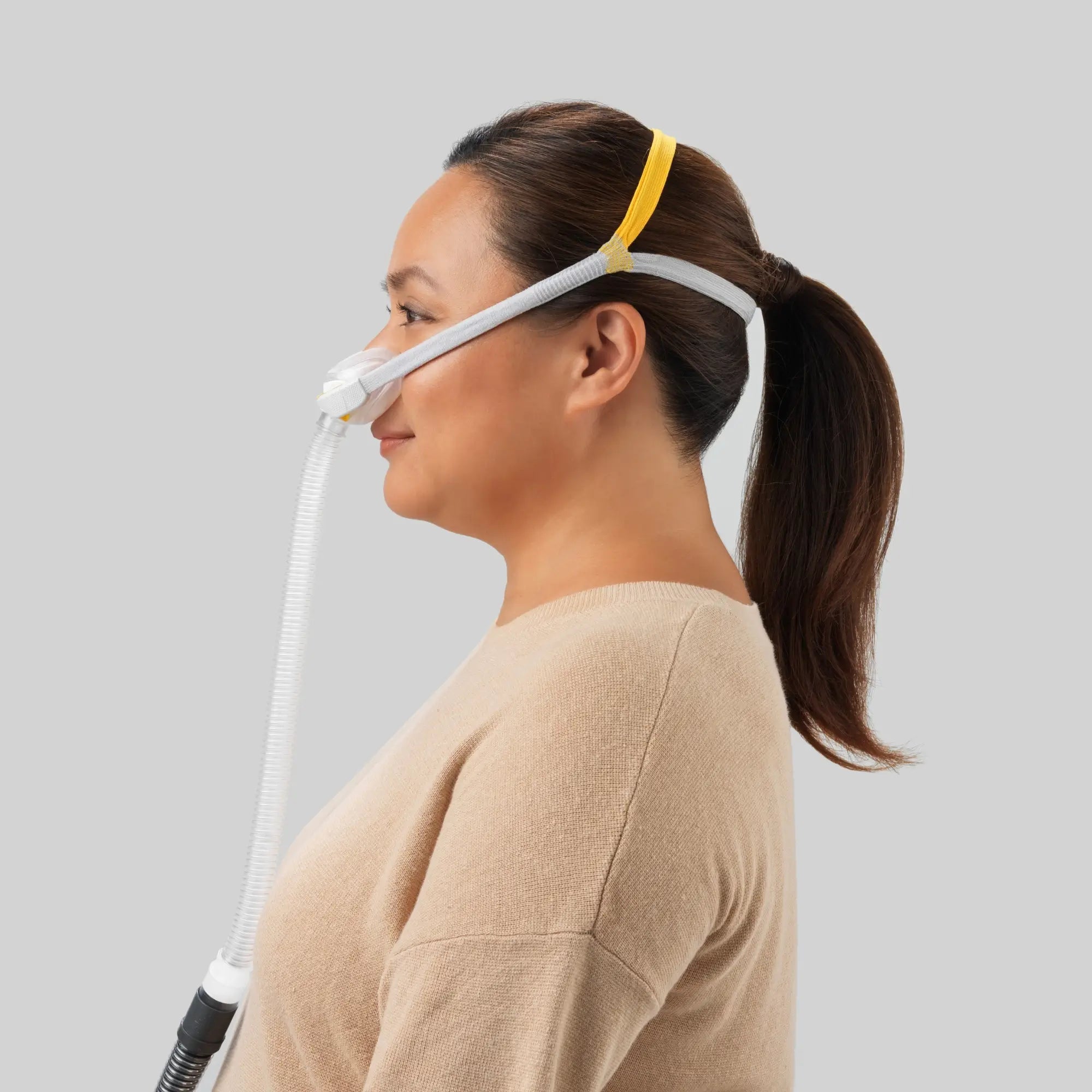 Woman using the F&P Solo Nasal CPAP Mask Autofit side view