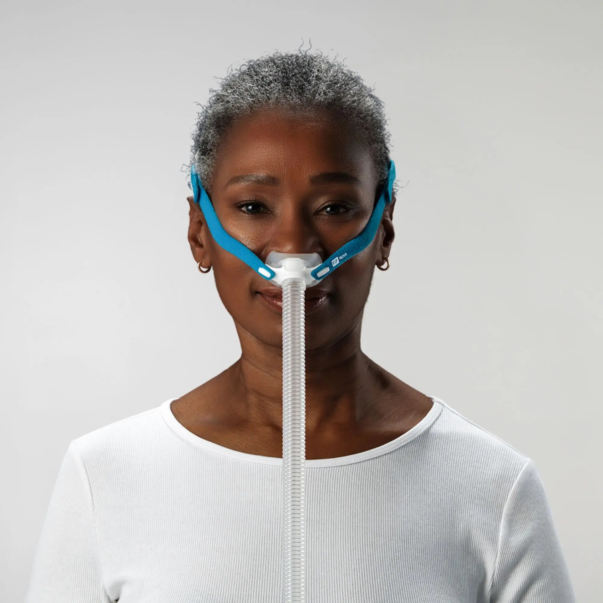 Woman using the F&P Nova Micro Nasal Pillows CPAP Mask front view   