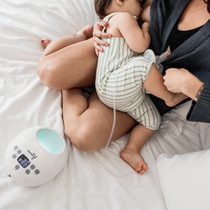 Woman carrying baby with Breast Pump.