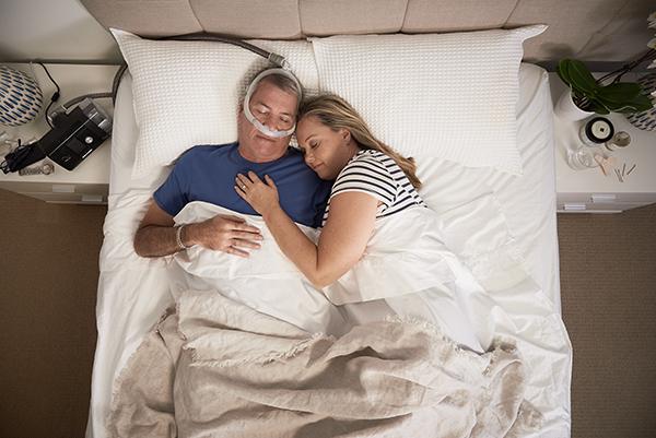 Man sleeping with ResMed AirFit P30 and his partner on the side