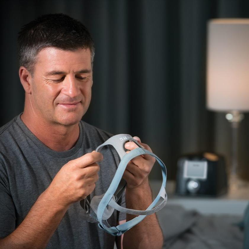 Man adjusting headgear for nasal mask.