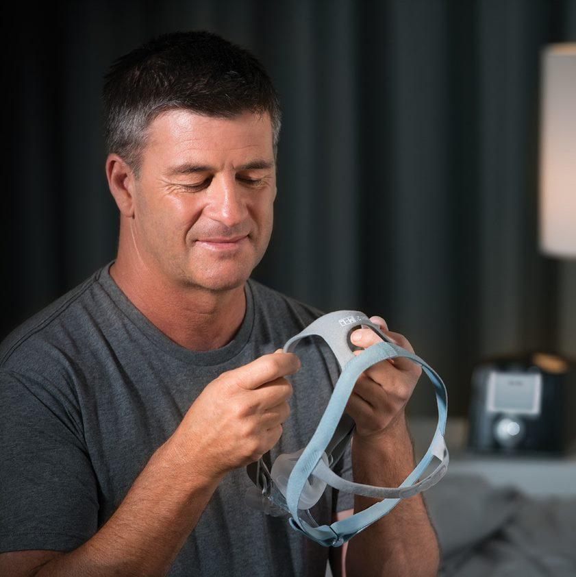 Man adjusting headgear for nasal mask.