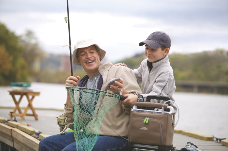 Man and kid fishing with Philips Respironics SimplyGo Portable Oxygen Concentrator Bundle (Continuous Flow & Pulse Dose) on the side