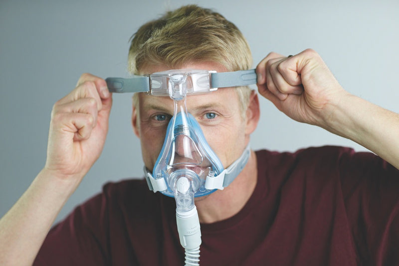 Man adjusting grey straps of Amara Full Face CPAP Mask with Gel & Silicone Cushions