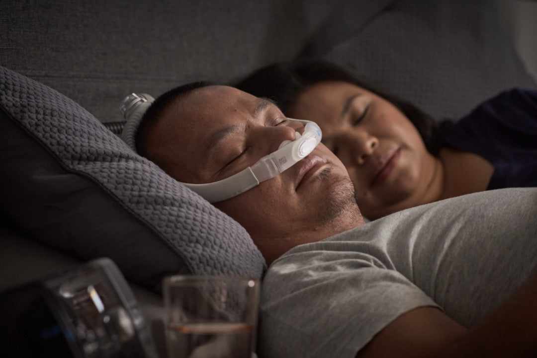 Man sleeping with ResMed AirFit P30 and his partner on the side.