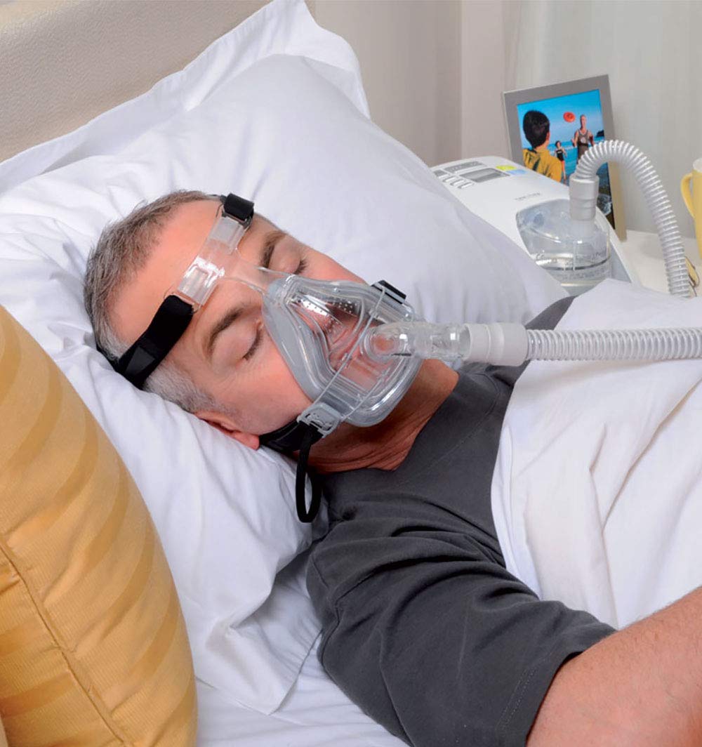 Man sleeping with Forma Full Face Mask with black Headgear by Fisher & Paykel.