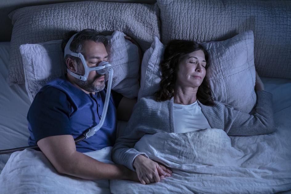 Couple sleeping and man wearing CPAP Airtouch mask.