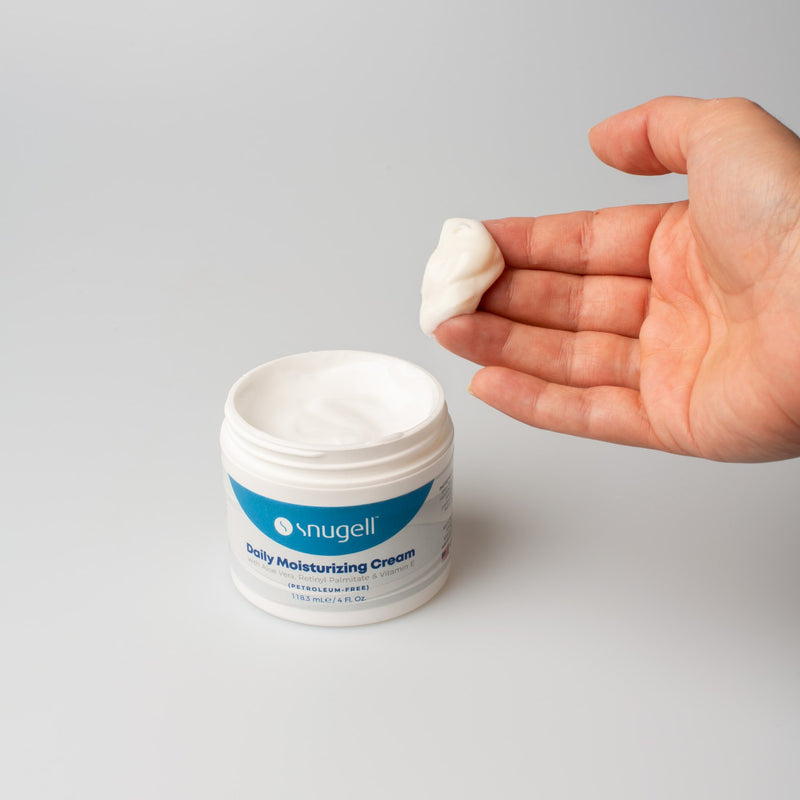 Front view of Snugell Daily Moisturizing Cream with model fingers