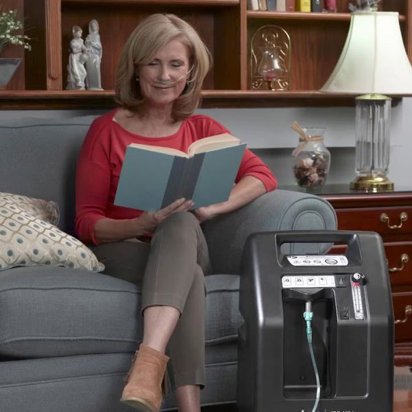 Woman reading a book while using Compact 525DS Oxygen Concentrator Bundle - 5 LPM