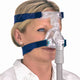 Side view of a woman using a clear mask with blue headgear and tube connector of the Ultra Mirage II Nasal CPAP Mask by ResMed.