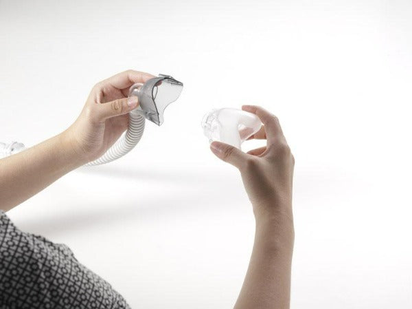 Person's hands attaching the Wizard 510 nasal cushion to the mask frame and tube