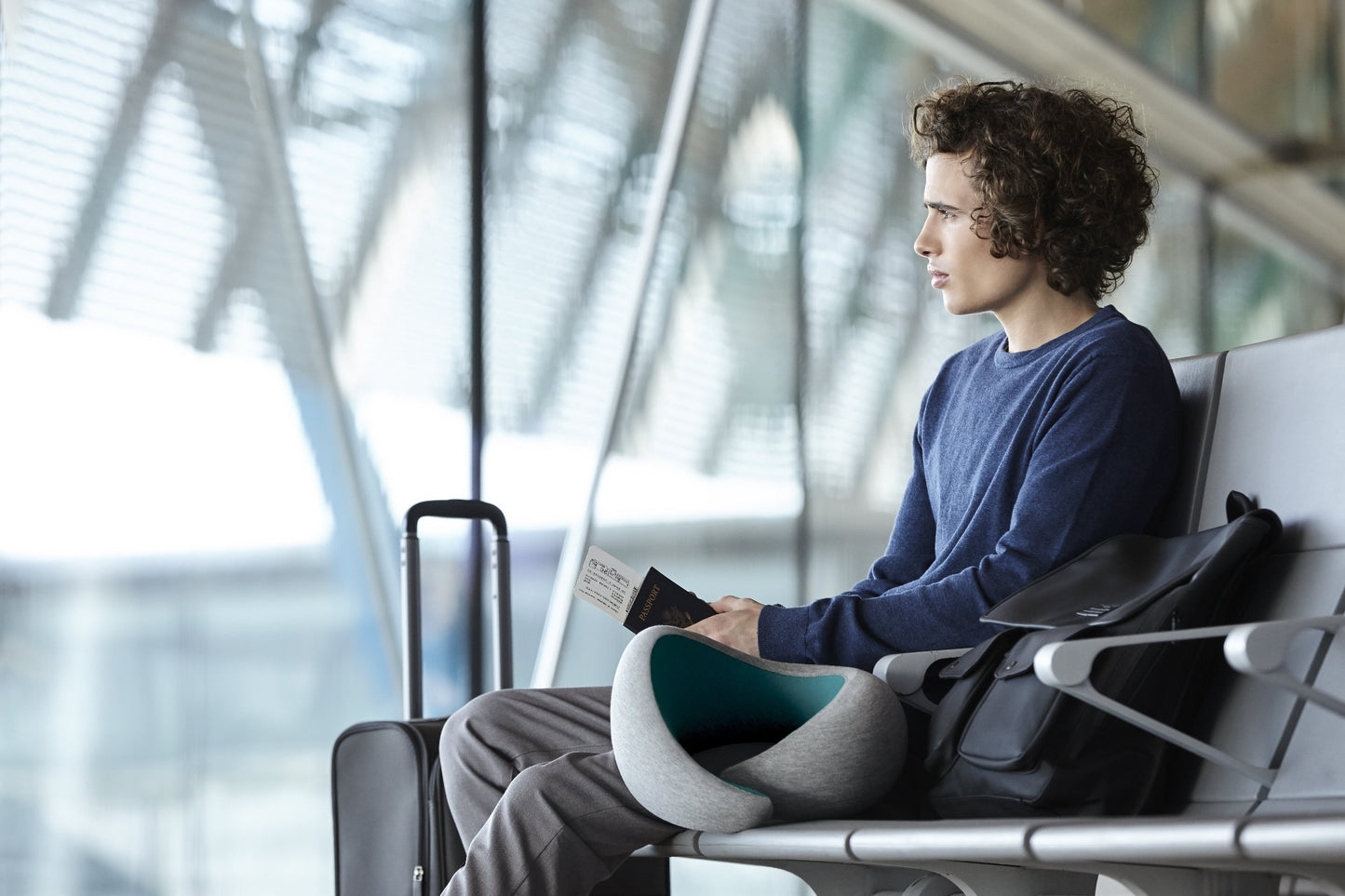 Man Waiting For Flight With Neck Pillow.