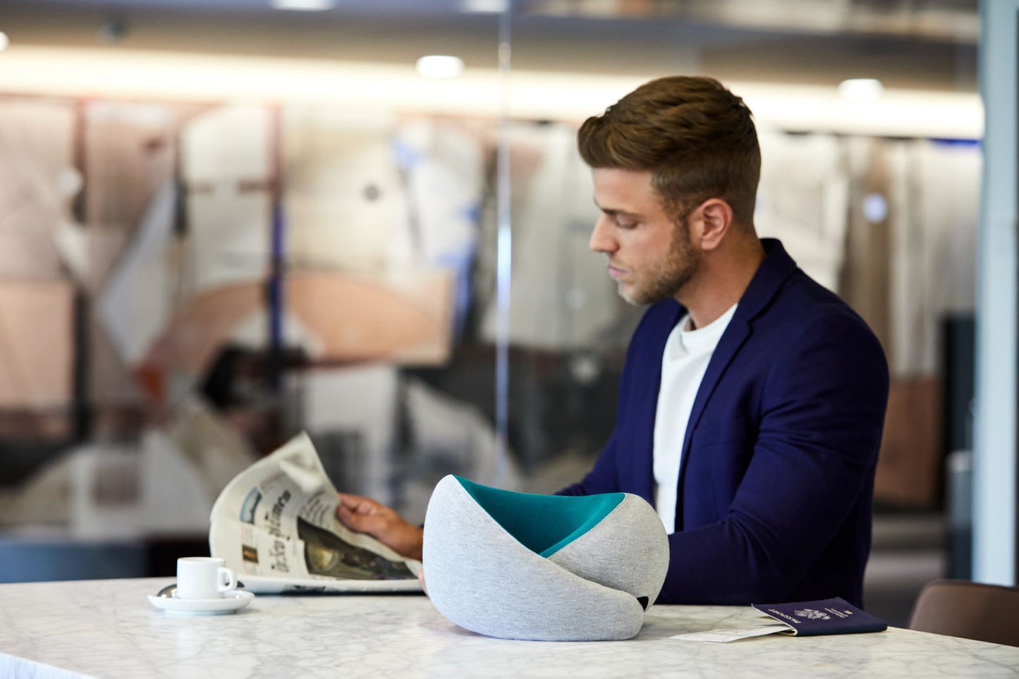 Man Reading News Paper Next To Neck Pillow.